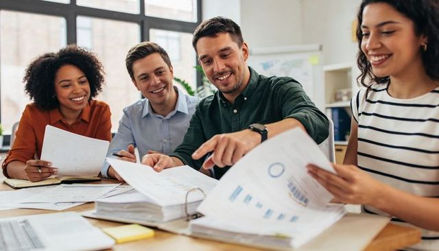 Diverse business team collaborating while reviewing charts and financial reports at desk