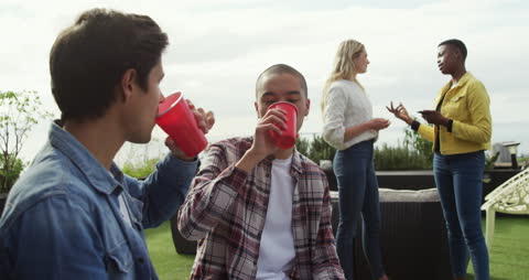 Friends Relaxing on Rooftop with Red Cups