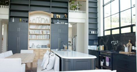 Double-Height Modern Kitchen with White Quartz Island, Dark Gray Cabinets and Mezzanine Bookshelves