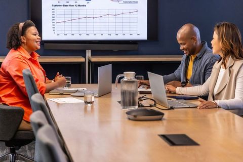 Multicultural team collaborating in modern boardroom reviewing upward growth chart
