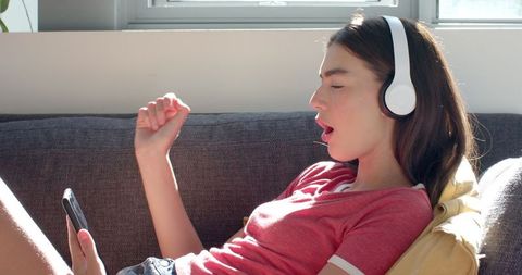 Teenage Girl Enjoying Music on Headphones in Sunny Living Room