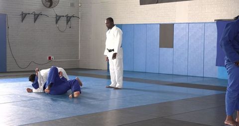 Instructor guiding grappling drills in martial arts dojo