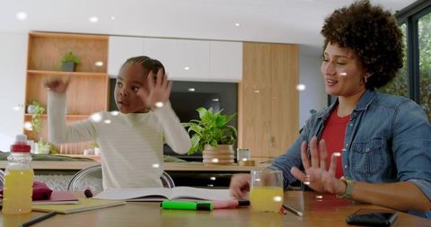 Parent and child studying together at modern kitchen table, laughing and learning