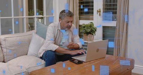Mature man holding credit card and typing on laptop for online banking and shopping at home