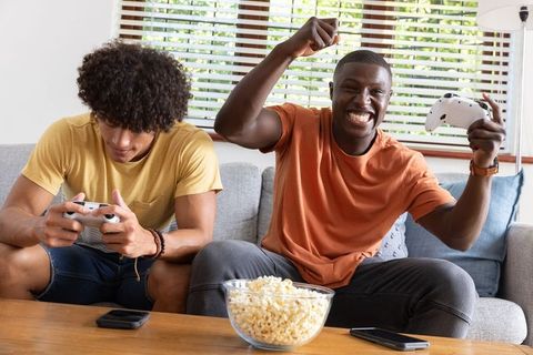 Two friends enjoying video games on comfortable couch