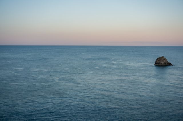 Serene Ocean View with Lone Rocky Island at Sunset - Download Free Stock Photos Pikwizard.com