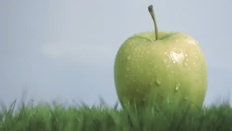 Fresh Green Apple with Water Droplets on Grass