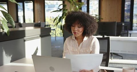 Professional Woman Analyzing Documents in Modern Office Workspace
