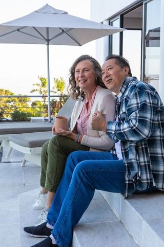 Senior couple relaxing on sunny terrace with ocean view
