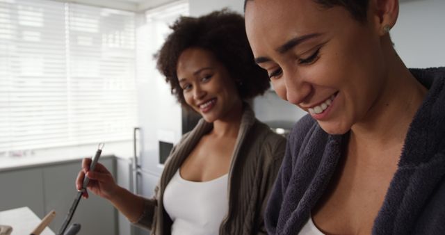 Two women cooking together and smiling in modern kitchen - Download Free Stock Images Pikwizard.com