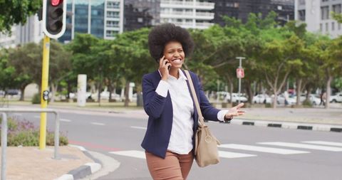 Smiling Businesswoman Talking on Smartphone While Walking in City