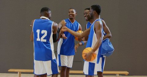 Basketball team celebrating, high-fiving and laughing courtside after practice