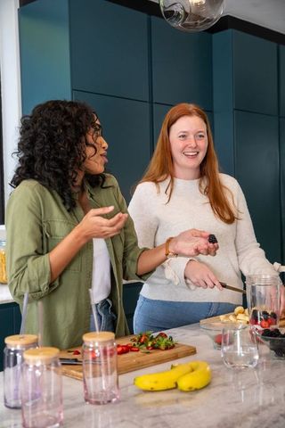Diverse Female Friends Preparing Fruit Smoothies in Modern Kitchen
