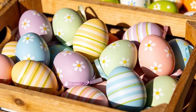 Pastel easter eggs with stripes and daisy motifs in rustic wooden crate