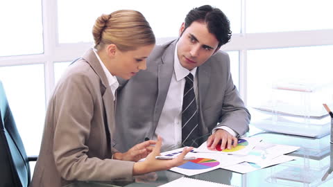 Focused Business Team Analyzing Colorful Charts in Modern Office