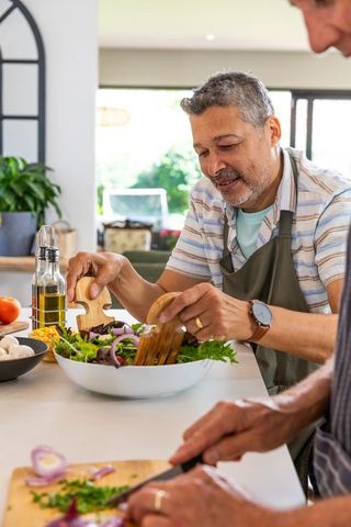 Senior Hispanic Men Preparing Salad Together in Modern Kitchen