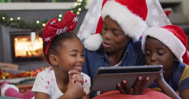 Happy african american mother with children using tablet. Spending quality time with family at christmas concept.