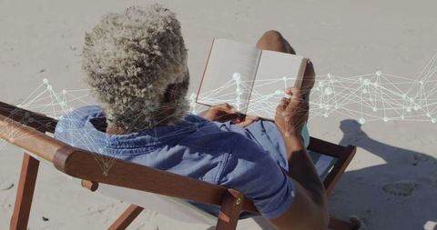 Elderly Man Enjoying Book and Digital Network at Beach