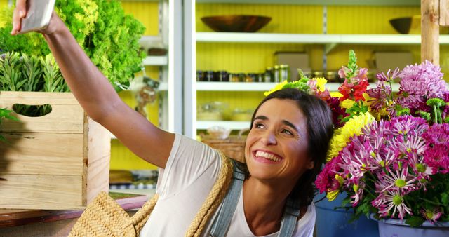 Woman taking selfie with flower from mobile phone at florist shop