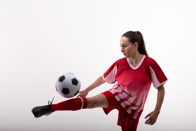 Confident female caucasian athlete practicing with soccer ball on white background with copy space. unaltered, sport, competition and game concept.