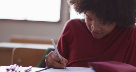 Joyful Biracial Student Writing in Classroom Setting