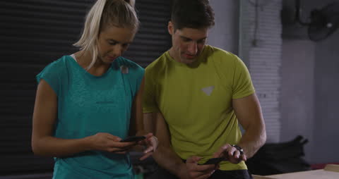 Athletic Couple Connecting on Smartphones at Gym