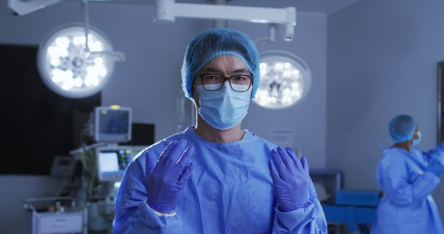Portrait of asian male surgeon wearing face mask, gloves, cap and scrubs in operating theatre - Download Free Stock Photos Pikwizard.com