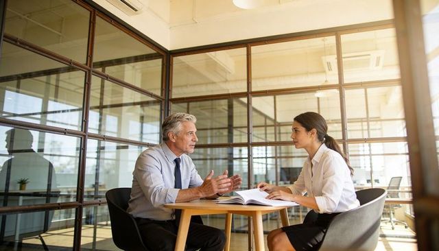 Male manager and female associate conducting performance review in modern glass office