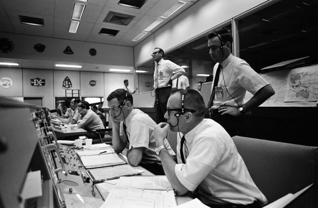 S69-34038 (18 May 1969) --- View of activity at the flight director's console in the Mission Operations Control Room in the Mission Control Center, Building 30, on the first day of the Apollo 10 lunar orbit mission. Seated are Gerald D. Griffin (foreground) and Glynn S. Lunney, Shift 1 (Black Team) flight directors. Milton L. Windler, standing behind them, is the flight director of Shift 2 (Maroon Team). In the center background, standing, is Dr. Christopher C. Kraft Jr., MSC Director of Flight Operations.