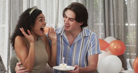 Multiracial couple celebrating birthday with birthday cake at party