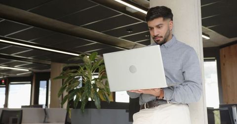 Young professional using laptop in contemporary open office