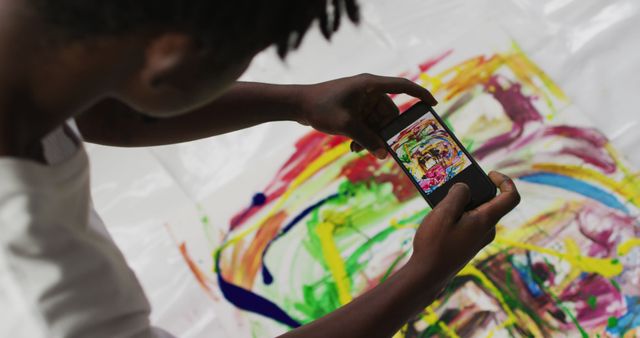 African american male artist taking a picture of his painting with a smartphone at art studio. art, hobby and creative occupation concept