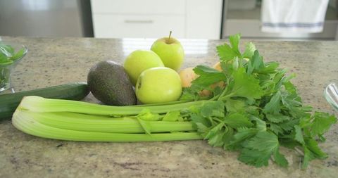 Fresh green celery with apples avocado and zucchini on granite kitchen countertop