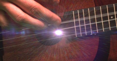 Close-up of guitar strumming with artistic lens flare