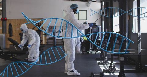 Commercial gym disinfection team spraying fitness equipment in protective suits