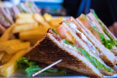 Toasted club sandwich with bacon, lettuce and tomato served with golden fries, close-up