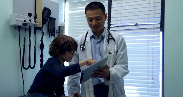 Pediatrician in White Coat Engaging with Young Patient Using Tablet in Clinic - Download Free Stock Images Pikwizard.com