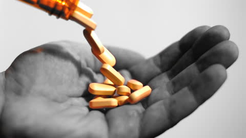 Orange Tablets Pouring into Hand in Slow Motion