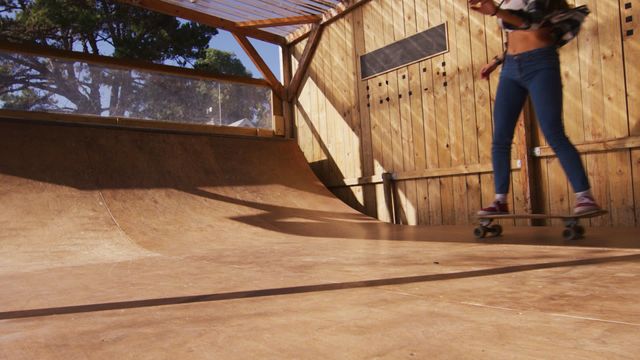 Video of a young woman skateboarding on a half pipe in a skate park. The wooden ramps and outdoor setting suggest a recreational sport popular among youth. Useful for content related to skateboarding, outdoor activities, youth culture, and sports hobbies.