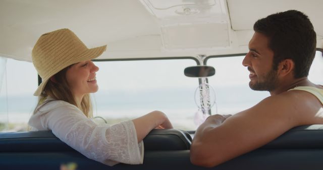 Smiling couple on road trip in summer, conversing while enjoying scenic beach views. Suitable for ads about travel, tourism, summer holidays, and couple activities.