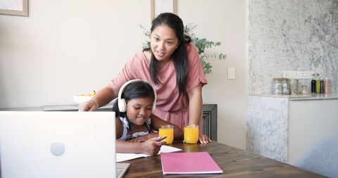 Mother Assisting Daughter with Homework at Kitchen Table