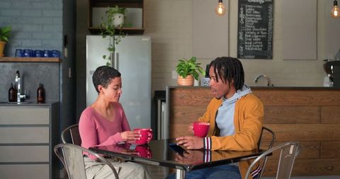 Casual cafe conversation between woman in pink and african american man in mustard jacket
