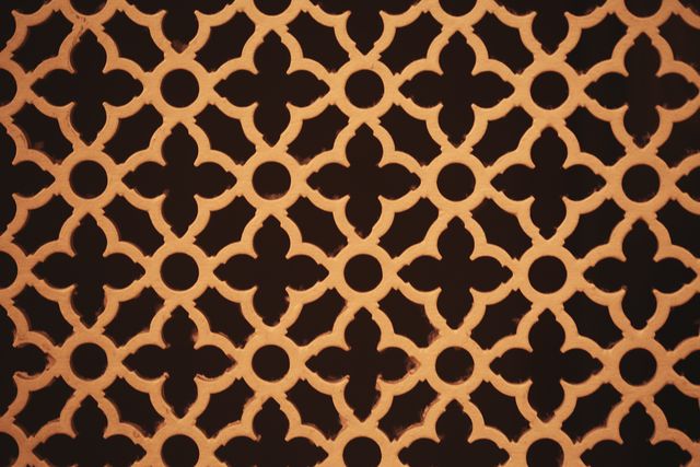 Geometric pattern featuring intricate, ornate design with warm golden light emphasizes the details. Suitable for use as a background, wallpaper, design element in graphic arts, textiles, or architectural inspiration. Great for projects requiring a decorative and elegant touch.