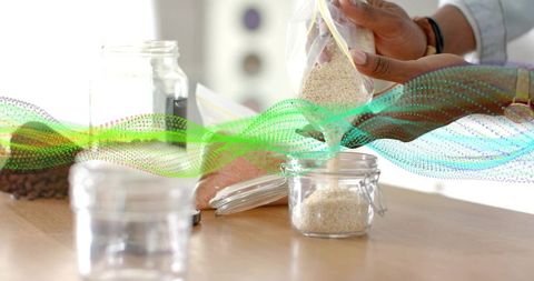 Hands Storing Grains in Glass Jar on Kitchen Table