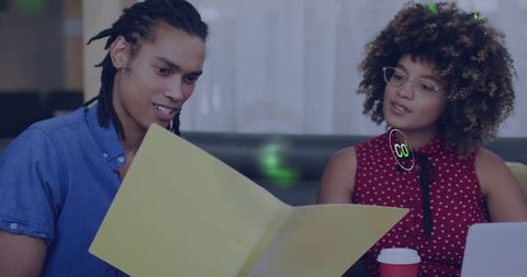 Reviewing yellow folder on sofa while collaborating in casual coworking lounge