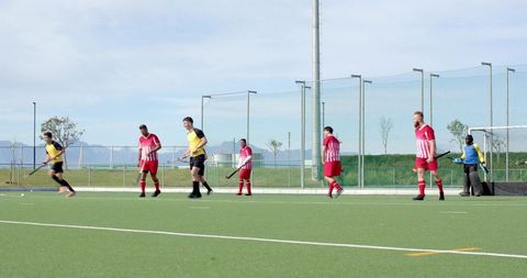 Field hockey players lining up for outdoor practice on turf field