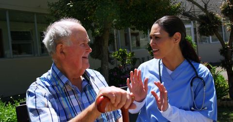 Senior man conversing with nurse in nursing home garden