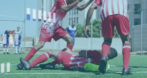 Youth soccer teammates helping fallen player on urban turf during small-sided match