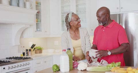 Senior African American Couple in Kitchen Unpacking Groceries