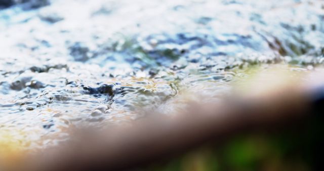 Abstract close-up showing rippling water surface with soft focus and vibrant reflections. Ideal for backgrounds, nature-themed projects, water conservation campaigns, and artistic designs promoting relaxation and tranquility.